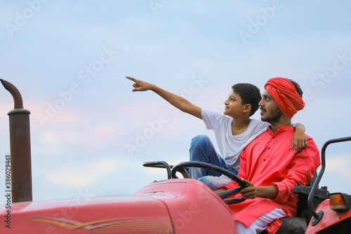 Indian farmer and his cute child enjoying tractor ride in agriculture field