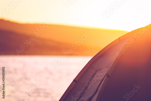 Camping tent near the seaside with an island view in the background and have flare effect. Background is out of focus  tent is in focus. Copy space available. Holiday  outdoor and family fun concept.