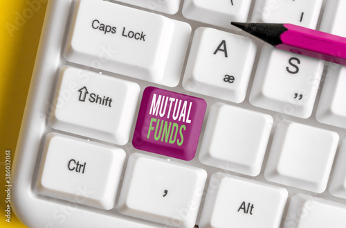Text sign showing Mutual Funds. Business photo showcasing An investment program funded by shareholders Individual Stocks Different colored keyboard key with accessories arranged on empty copy space photo