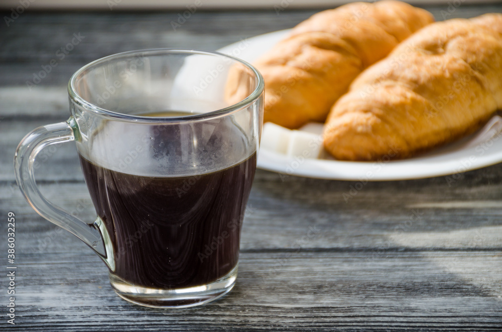 Still life with cup of coffee and croissant on the wooden background. Old retro camera and postcard are near the cup. Still life with cup of coffee and croissant on the wooden background. Old retro camera and postcard are near the cup.