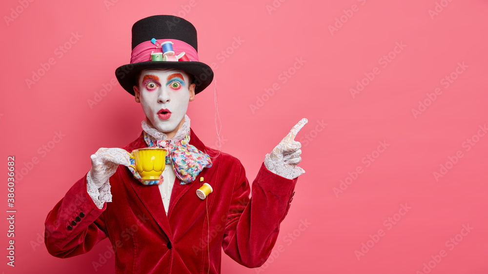 Obraz na plátně Insane mysterious unique character obsessed with tea drinking dressed fashionably has big hat points at upper right corner against pink background