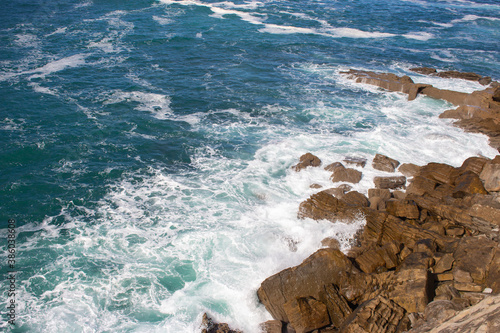 Waves crashing on rocks, Atlantic Ocean. Azure sea waves with white foam breaking on coast. Splash of aquamarine sea water. Scenic splashing waves. Amazing seascape. Water in motion. Sea wallpaper.