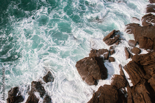 Waves crashing on rocks, Atlantic Ocean. Azure sea waves with white foam breaking on coast. Splash of aquamarine sea water. Scenic splashing waves. Amazing seascape. Water in motion. Sea wallpaper.