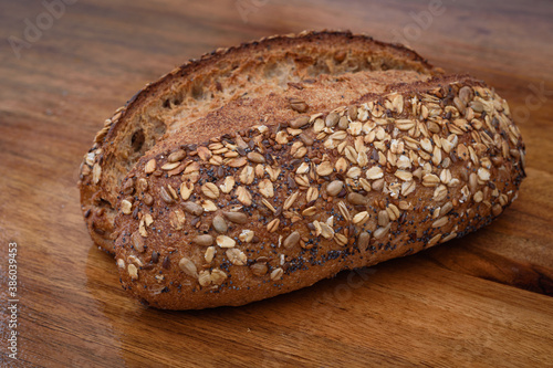 Handmade loaf of yellow wheat bread sprinkled with various cereals, close up bread, isolated. 