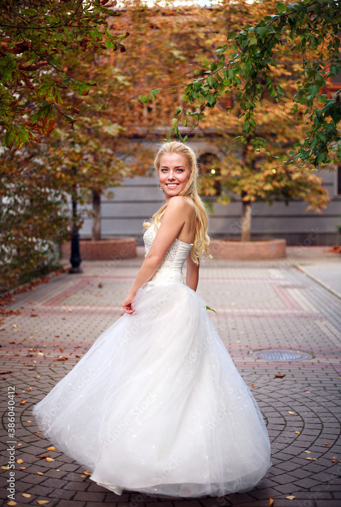 Young happy bride in wedding white dress in autumn yard whirl emotionally Young happy bride in wedding white dress in autumn yard whirl emotionally