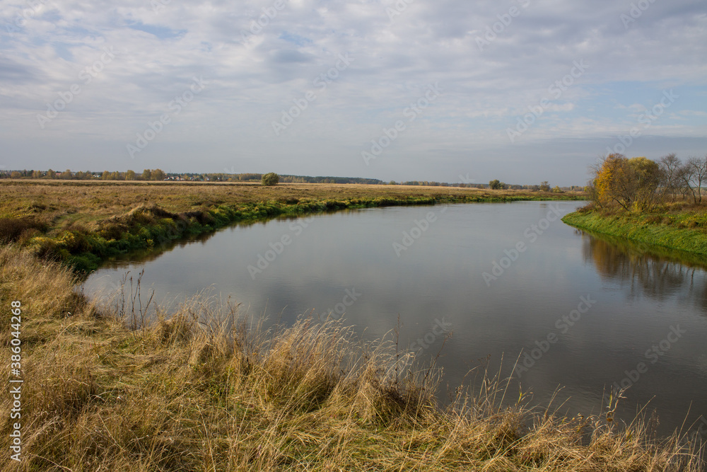 Autumn landscape - bend of the river with yellow grass and reflection of the cloudy sky and space for copying Autumn landscape - bend of the river with yellow grass and reflection of the cloudy sky and space for copying