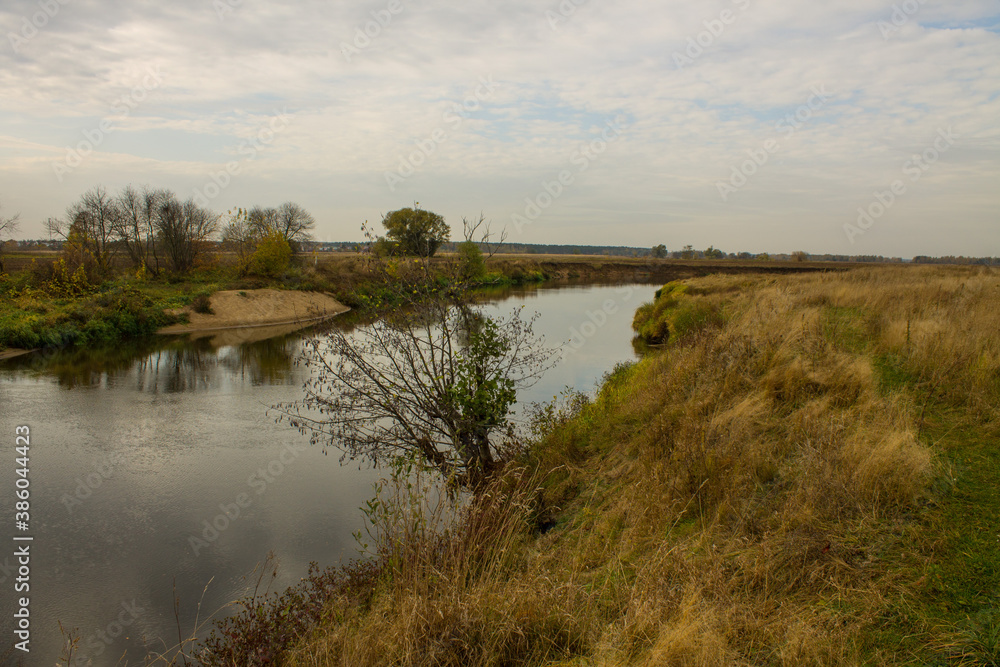 Autumn landscape - bend of the river with yellow grass and reflection of the cloudy sky and space for copying Autumn landscape - bend of the river with yellow grass and reflection of the cloudy sky and space for copying