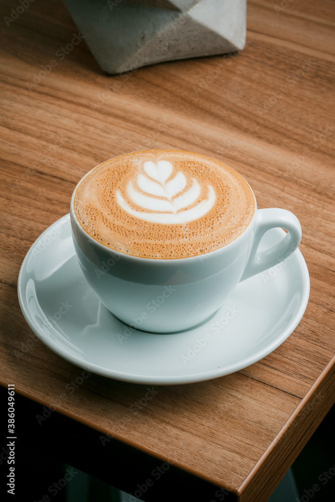 Beautiful cup of cappuccino with latte art in space wooden background. Fashionable toning. Minimal composition, hipster vibration. Top view, flat copy space for text. Beautiful cup of cappuccino with latte art in space wooden background. Fashionable toning. Minimal composition, hipster vibration. Top view, flat copy space for text.