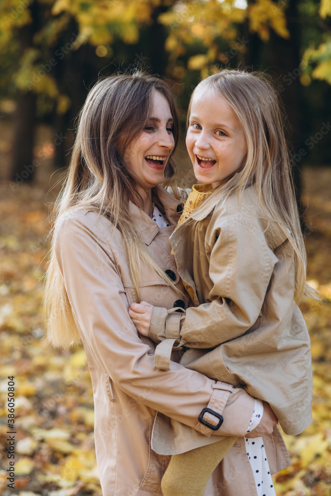 Happy mother and her beautiful daughter have fun and walk in the autumn park.