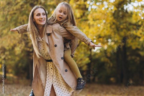Happy mother and her beautiful daughter have fun and walk in the autumn park.