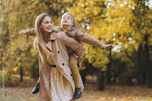 Happy mother and her beautiful daughter have fun and walk in the autumn park.