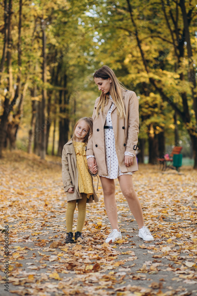 Fototapeta premium Happy mother and her beautiful daughter have fun and walk in the autumn park.