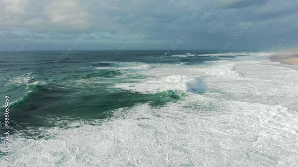 Picturesque large azure waves with heavy white foam roll on empty beach under cloudy sky on nice summer day bird eye view Picturesque large azure waves with heavy white foam roll on empty beach under cloudy sky on nice summer day bird eye view