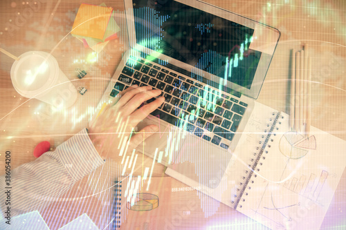 Double exposure of man's hands typing over computer keyboard and forex graph hologram drawing. Top view. Financial markets concept.