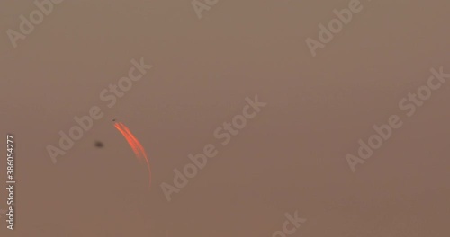 Airplane close up from long distance, orange contrails in the sky.