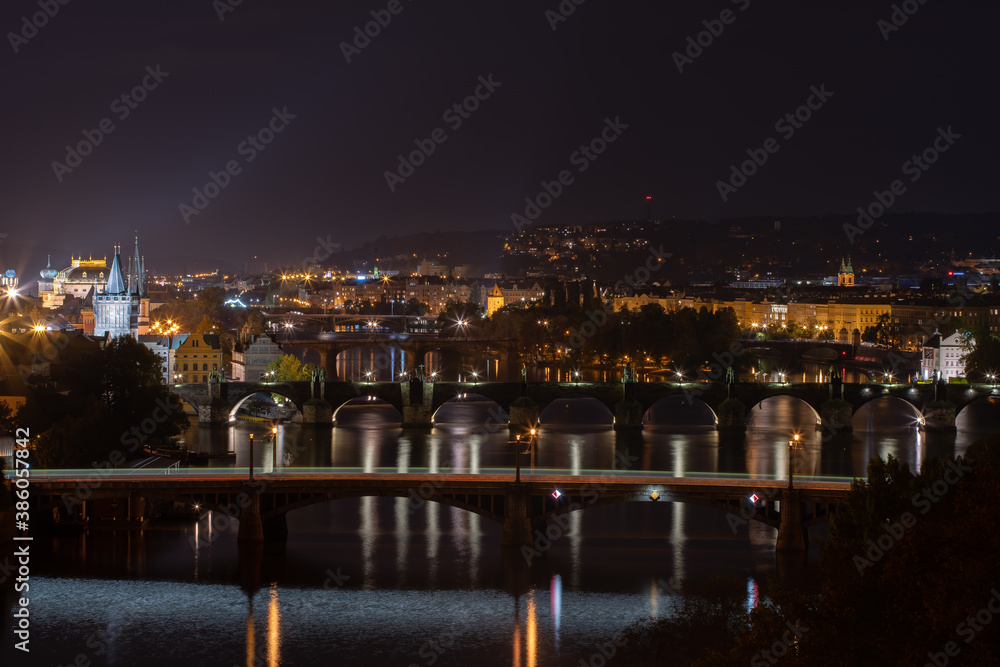 
panoramic view of the illuminated city of Prague and the Vltava river and the bridges on it and the light from the street lights in the city center at night