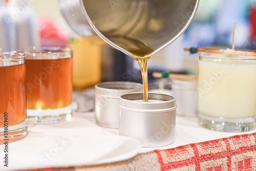 Creative occupation of candle making showing the pouring of liquid wax into jars