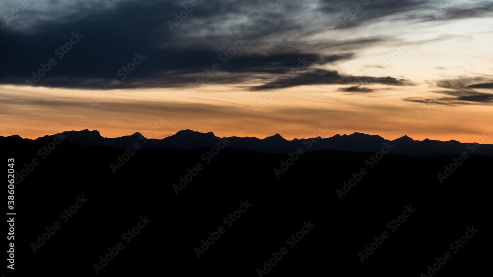 Majestic Canadian landscape and Rocky Mountain range peak silhouette in the distance at sunset. Beautiful orange sky and rocky mountains on the horizon