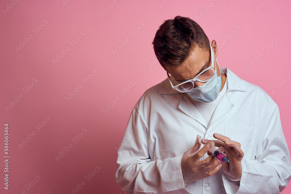 A doctor in a medical mask and gloves holds a syringe in the hands of an injection laboratory A doctor in a medical mask and gloves holds a syringe in the hands of an injection laboratory