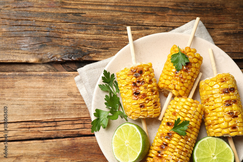 Tasty grilled corn on wooden table, top view. Space for text