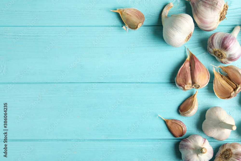 Fresh unpeeled garlic bulbs and cloves on light blue wooden table, flat lay with space for text. Organic product Fresh unpeeled garlic bulbs and cloves on light blue wooden table, flat lay with space for text. Organic product