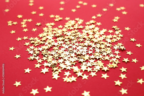 Gold confetti stars on red background  closeup. Christmas celebration