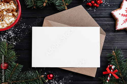 Flat lay composition with Christmas decor and blank card on black wooden table. Space for text