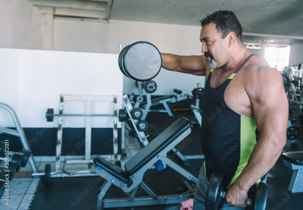 mature man does shoulder exercises in gym, muscular man mature man does shoulder exercises in gym, muscular man