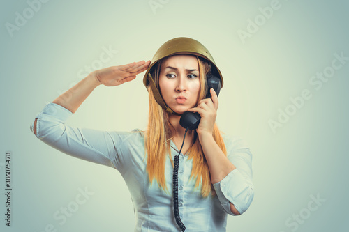 Obraz na plátně Woman in military helmet talking at phone giving her salute to captain