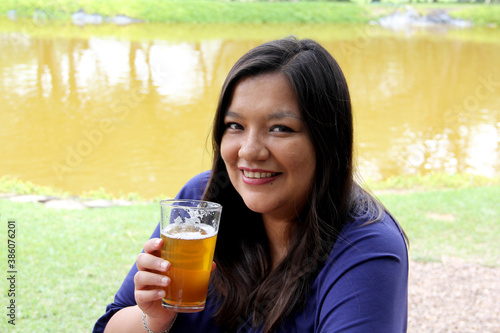 
black hair latin woman drinking beer outdoors taking selfie with view of san miguel de allende parish in guanajoato mexico photo