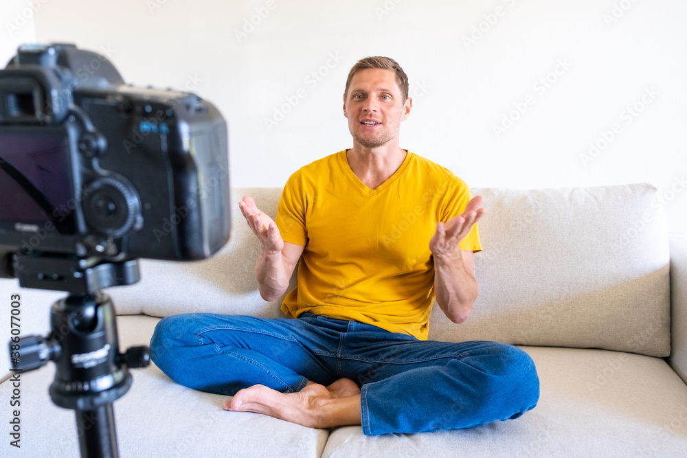 Happy handsome young male speaker sitting in front of camera recording webinars training videos at home. Smiling experienced guy make a video for his blog. Happy handsome young male speaker sitting in front of camera recording webinars training videos at home. Smiling experienced guy make a video for his blog.