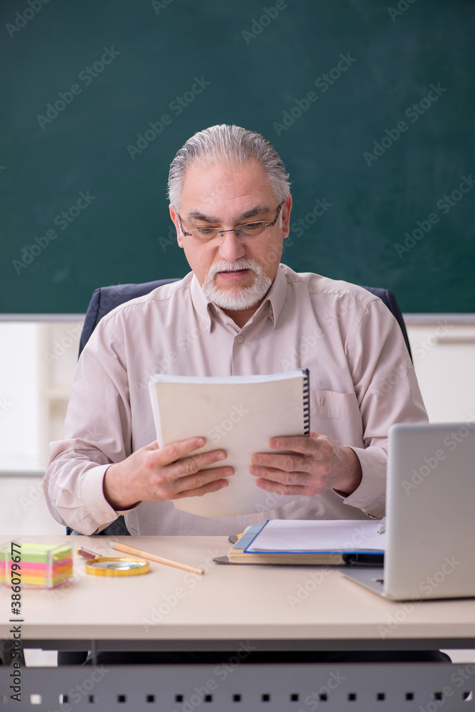 Old male teacher in the classroom Old male teacher in the classroom