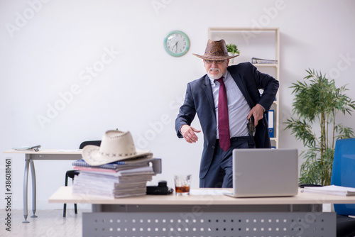 Funny old boss in cowboy hat in the office