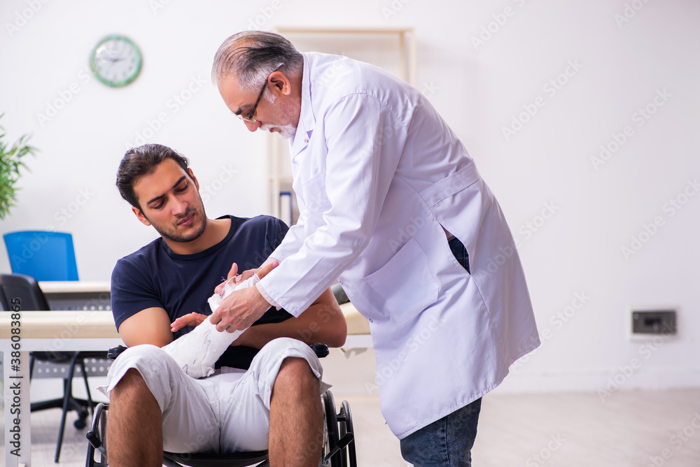 Young injured man visiting experienced male doctor traumatologis Young injured man visiting experienced male doctor traumatologis