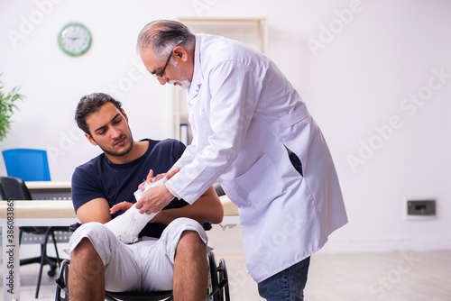 Young injured man visiting experienced male doctor traumatologis