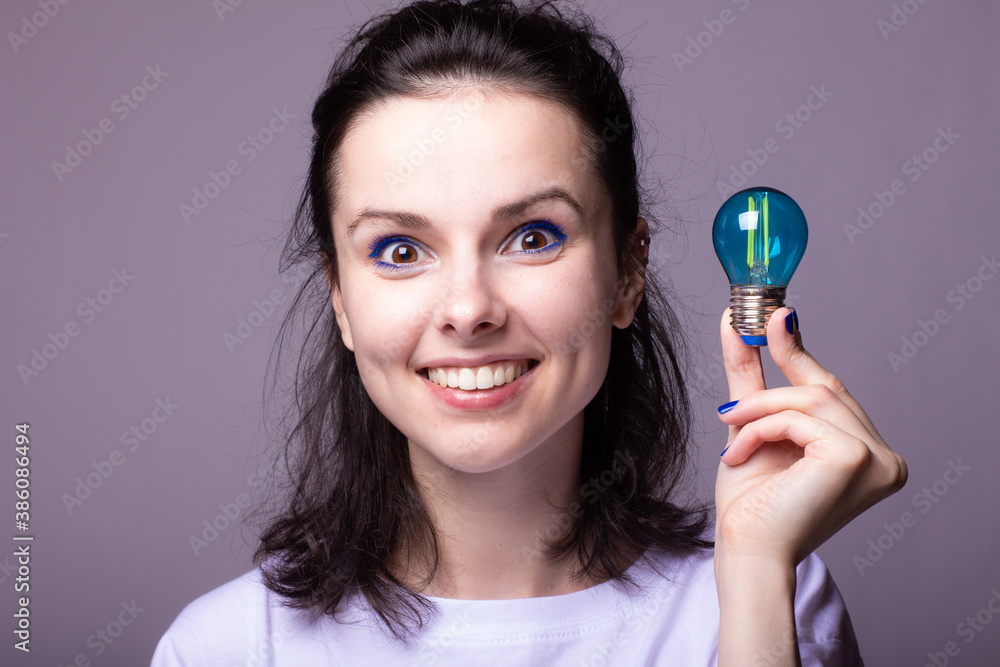 beautiful girl in a white t-shirt holds a blue light bulb in her hands beautiful girl in a white t-shirt holds a blue light bulb in her hands