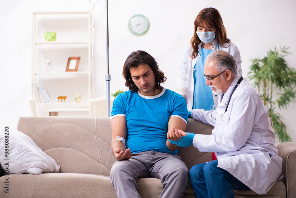 Two doctors visiting sick young man at home Two doctors visiting sick young man at home