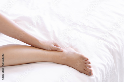 Closeup woman legs on white bed with over light form window, beauty and skin care concept, selective focus © mraoraor