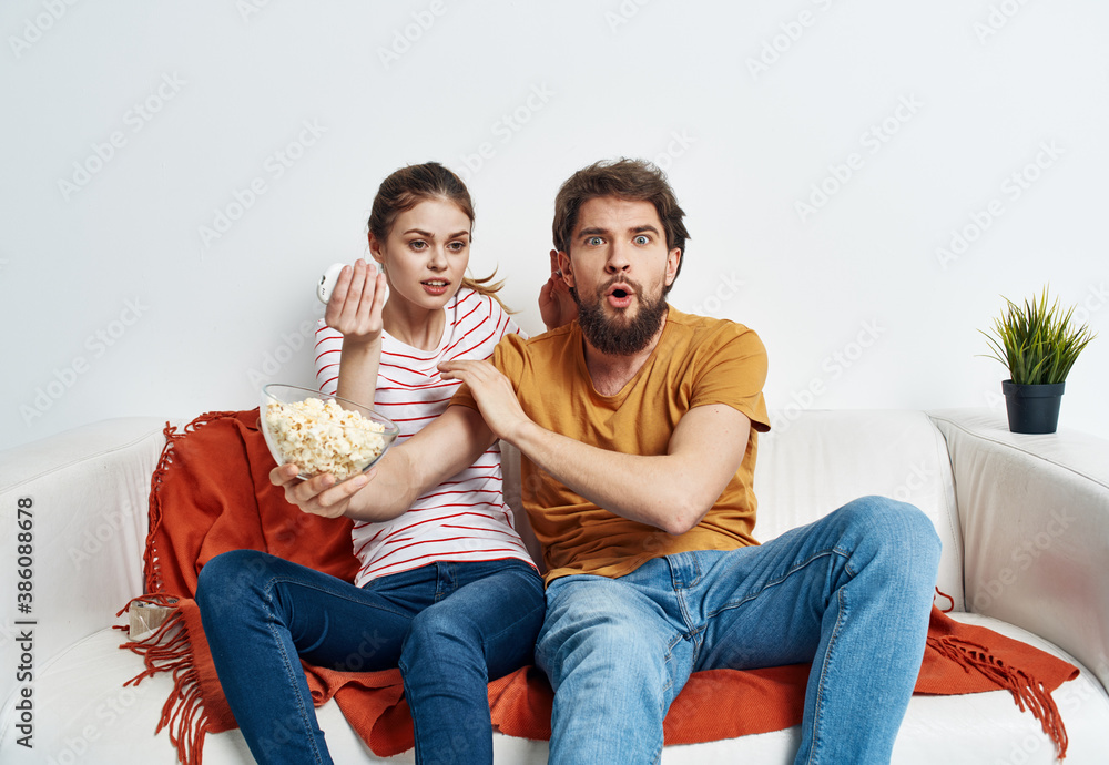 friends man and woman with popcorn in a plate indoors on sofa interior