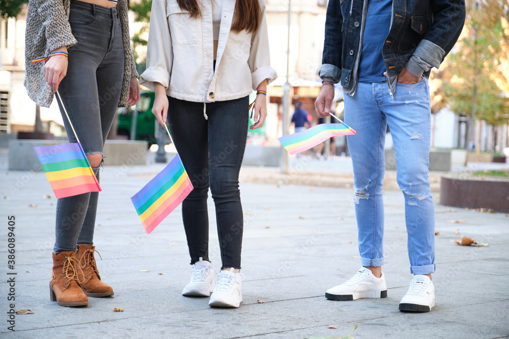 Three unrecognizable friends holding LGBT flags after the Pride Parade. LGBT pride celebration. Three unrecognizable friends holding LGBT flags after the Pride Parade. LGBT pride celebration.