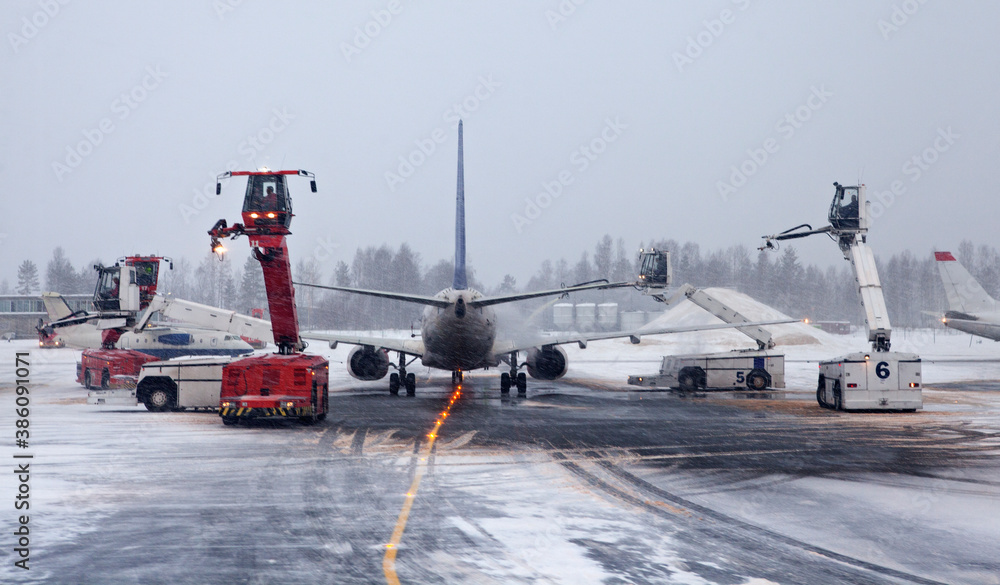 Deicing trucks and airplane at airport during heavy snow fall