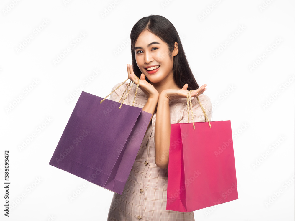 Portrait of smiling beautiful asian woman wearing dress and holding shopping bags isolated on white background. Portrait of smiling beautiful asian woman wearing dress and holding shopping bags isolated on white background.