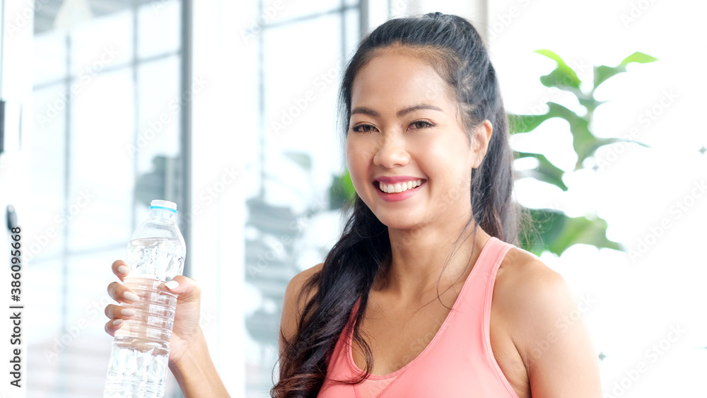 Young beautiful asian woman drinking water after exercise at home, Happy asia girl smiling while holding water bottle, people and healthy lifestyles Young beautiful asian woman drinking water after exercise at home, Happy asia girl smiling while holding water bottle, people and healthy lifestyles