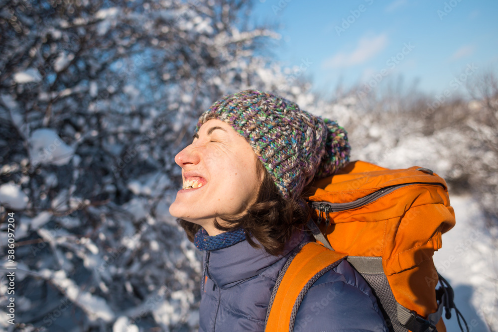 Smiling woman with a backpack on a background of a snowy forest