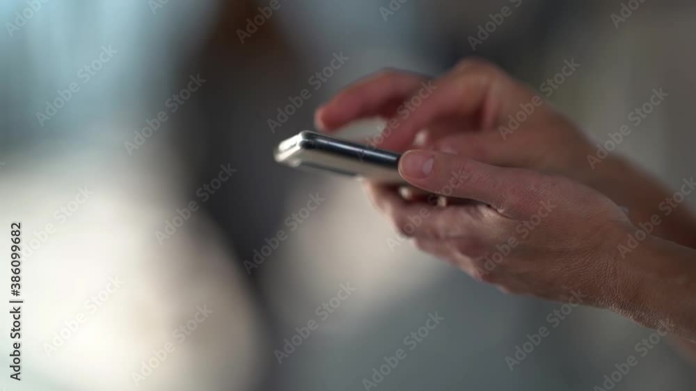 Side view. A woman's hands use a smartphone to type a message in a public place. Close-up of the hand. Side view. A woman's hands use a smartphone to type a message in a public place. Close-up of the hand.