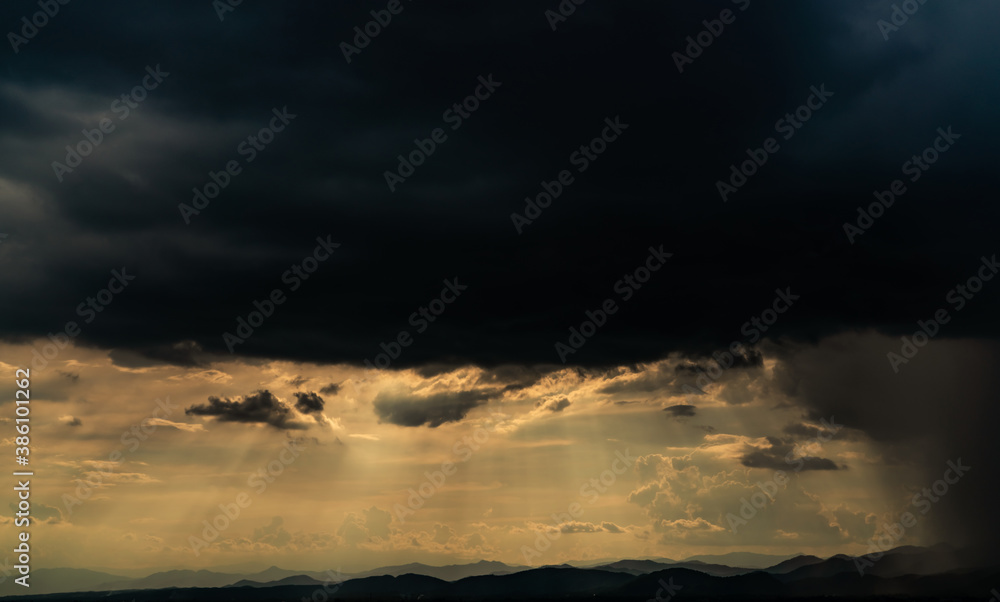 Heaven sky with god light over mountain range. Sun rays through dark clouds. Stormy sky. Golden sunlight shine from heaven sky for hope and faithful. Landscape of mountain layer. Beauty in nature. Heaven sky with god light over mountain range. Sun rays through dark clouds. Stormy sky. Golden sunlight shine from heaven sky for hope and faithful. Landscape of mountain layer. Beauty in nature.