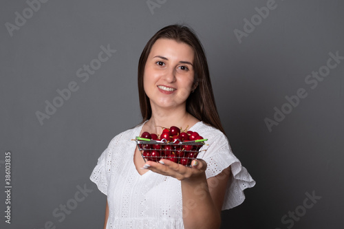 Beautiful woman is holding ripe red berries. Young woman eats sweet cherries.