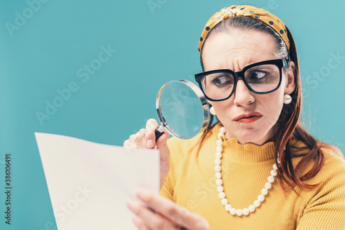 Woman checking carefully a document using a magnifier