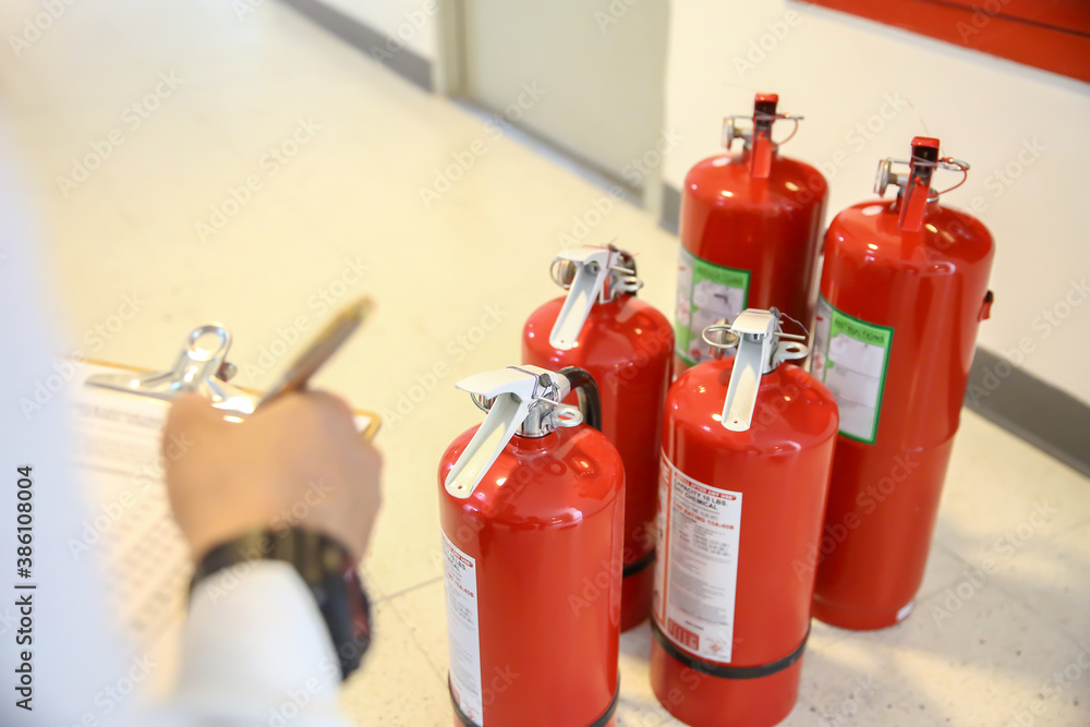 Obraz premium Fire fighter are checking the red fire extinguishers tank in the building concepts of fire prevention emergency and safety rescue of fire services and training.