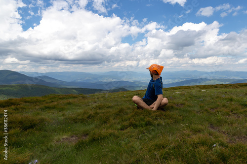 Guy looks at the beautiful mountains, sitting in the meadow. © vallerato